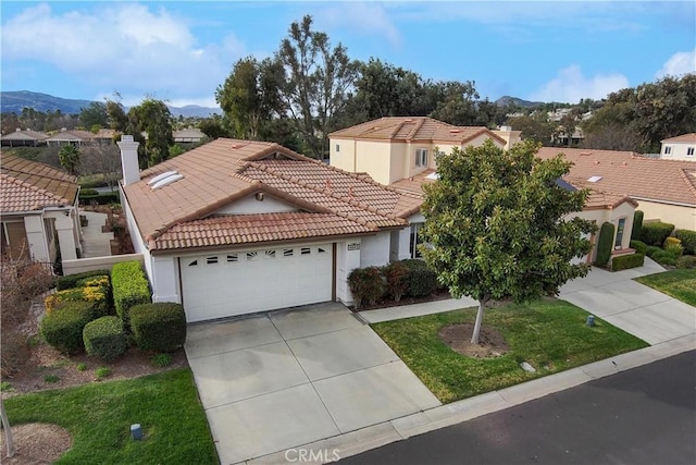 mediterranean / spanish-style home with a garage, a mountain view, concrete driveway, and a tiled roof