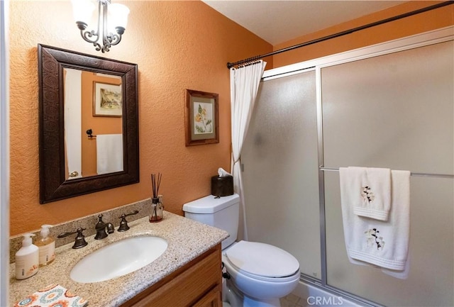 full bathroom with a textured wall, vanity, a shower stall, and toilet