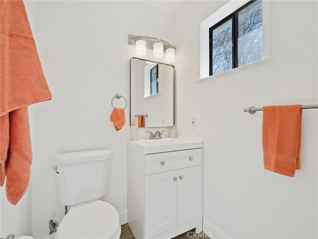 bathroom with vanity, toilet, and baseboards