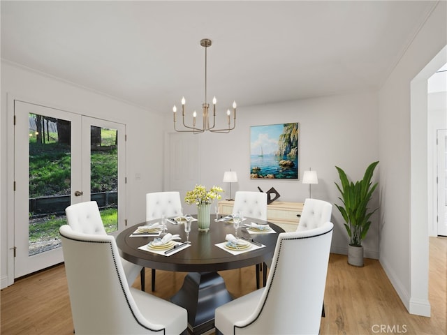 dining area featuring light wood-style floors, baseboards, a chandelier, and french doors