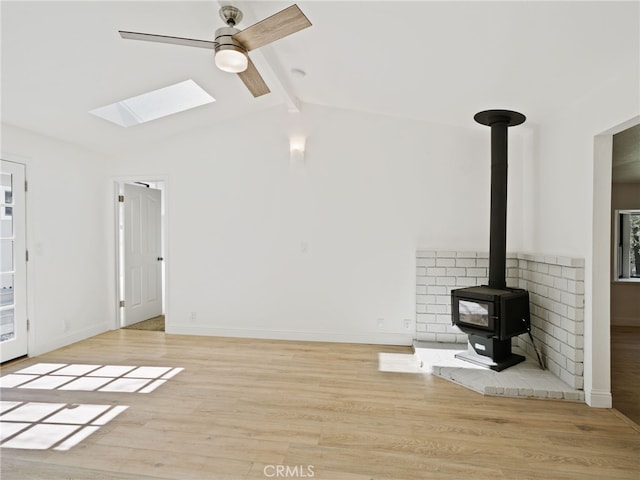 unfurnished living room featuring a wood stove, lofted ceiling with beams, baseboards, and wood finished floors