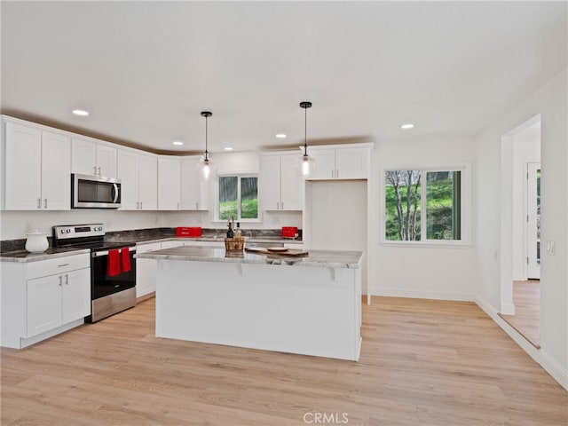 kitchen featuring light wood-style flooring, appliances with stainless steel finishes, white cabinets, and a center island