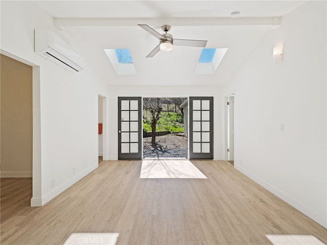 unfurnished living room featuring vaulted ceiling with skylight, a wall unit AC, ceiling fan, wood finished floors, and french doors