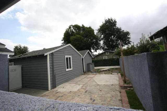 view of property exterior featuring a patio area, a fenced backyard, and an outbuilding