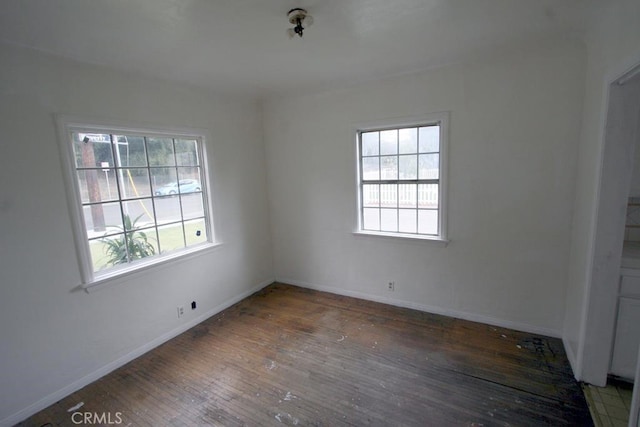 spare room with wood-type flooring and baseboards