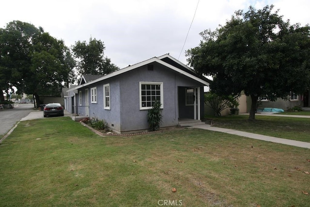 bungalow with a front lawn and stucco siding