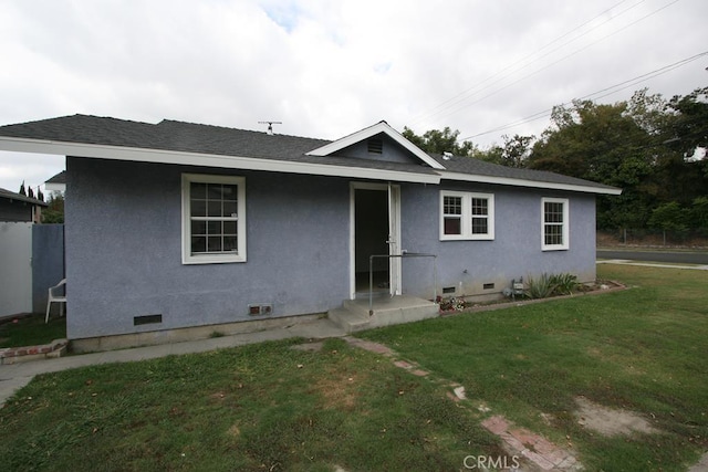 view of front facade with a front lawn, crawl space, a shingled roof, and stucco siding