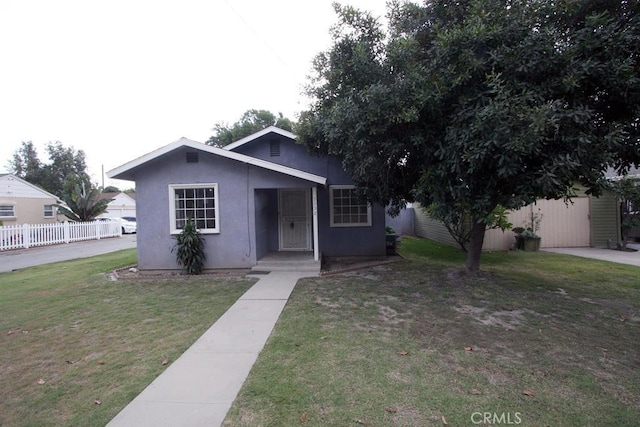 view of front facade with a front yard, fence, and stucco siding