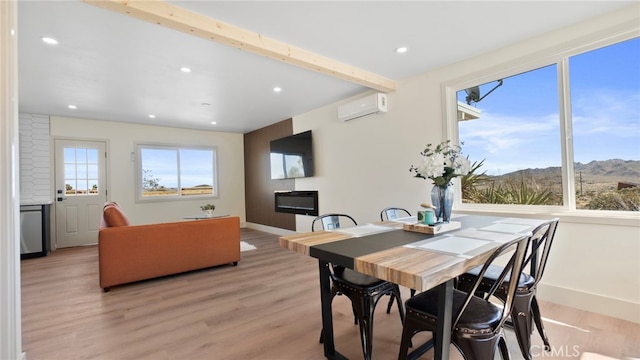 dining room with beamed ceiling, plenty of natural light, light wood-style flooring, and a wall mounted AC