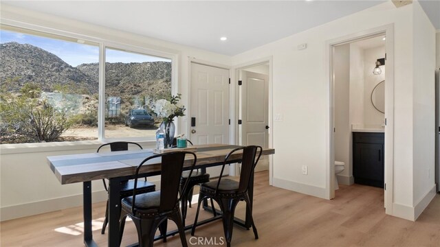 dining area featuring recessed lighting, light wood-style flooring, a mountain view, and baseboards