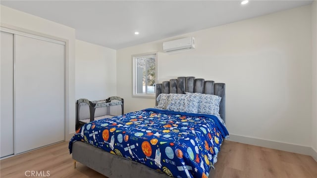 bedroom with baseboards, a wall unit AC, recessed lighting, wood finished floors, and a closet