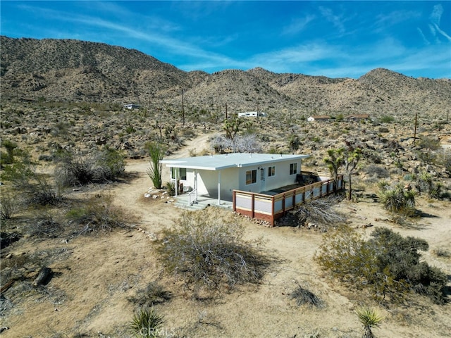 view of front of home with a deck with mountain view, a garage, and stucco siding