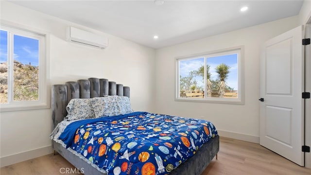 bedroom with multiple windows, a wall mounted air conditioner, baseboards, and wood finished floors