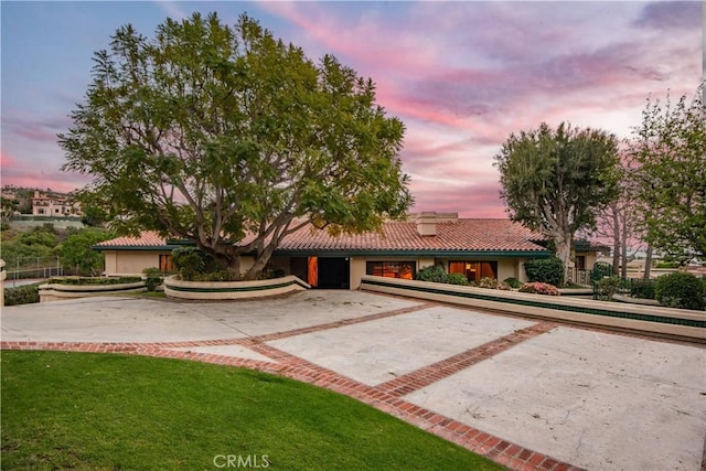 view of front of home with a tile roof, a lawn, and a chimney