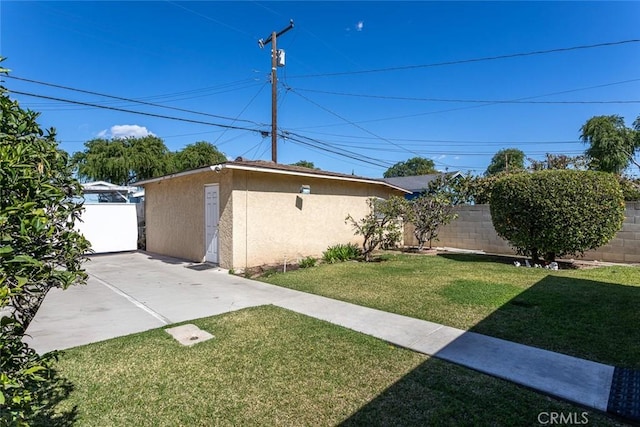 view of home's exterior featuring an outbuilding, a yard, fence, and stucco siding