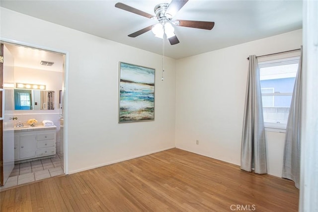 unfurnished bedroom featuring light wood-style floors, visible vents, connected bathroom, and a ceiling fan