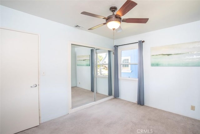 empty room with carpet floors, visible vents, and a ceiling fan