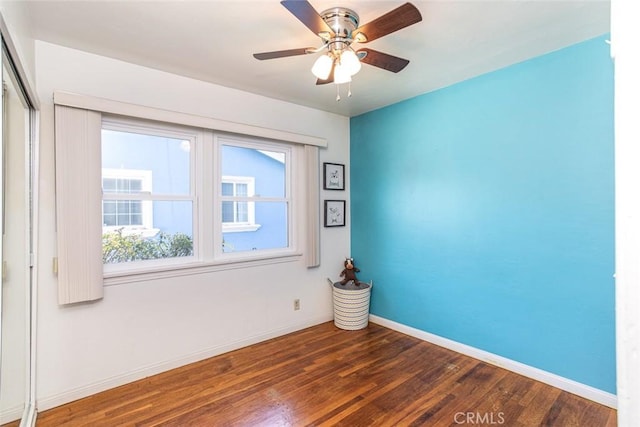 empty room with a ceiling fan, baseboards, and wood finished floors