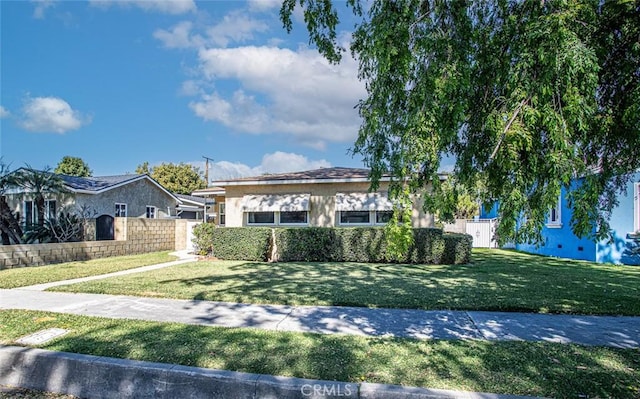 view of front facade featuring a front yard, fence, and stucco siding