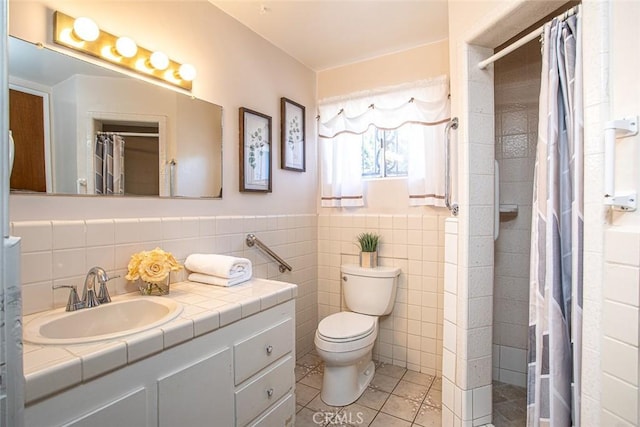 full bathroom with a tile shower, tile walls, toilet, and vanity