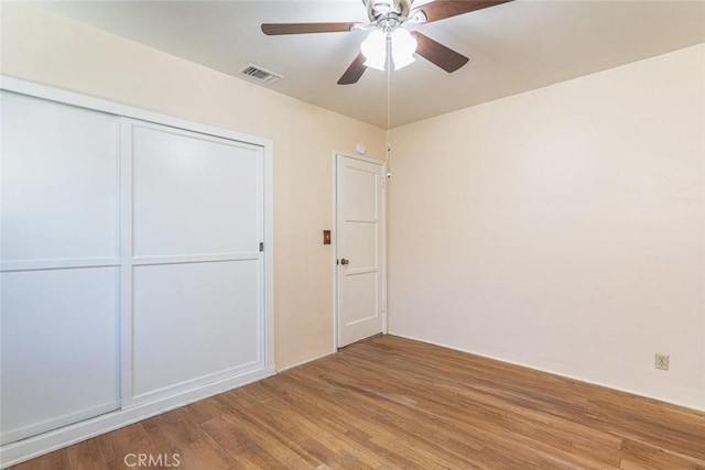 unfurnished bedroom featuring light wood-style flooring, visible vents, ceiling fan, and a closet