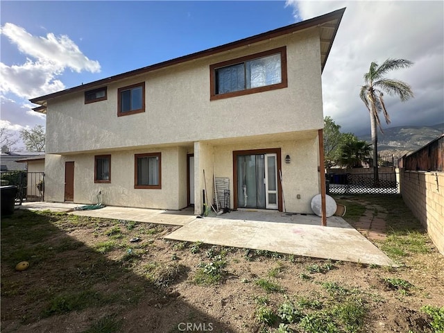 back of house with a fenced backyard, a patio, and stucco siding