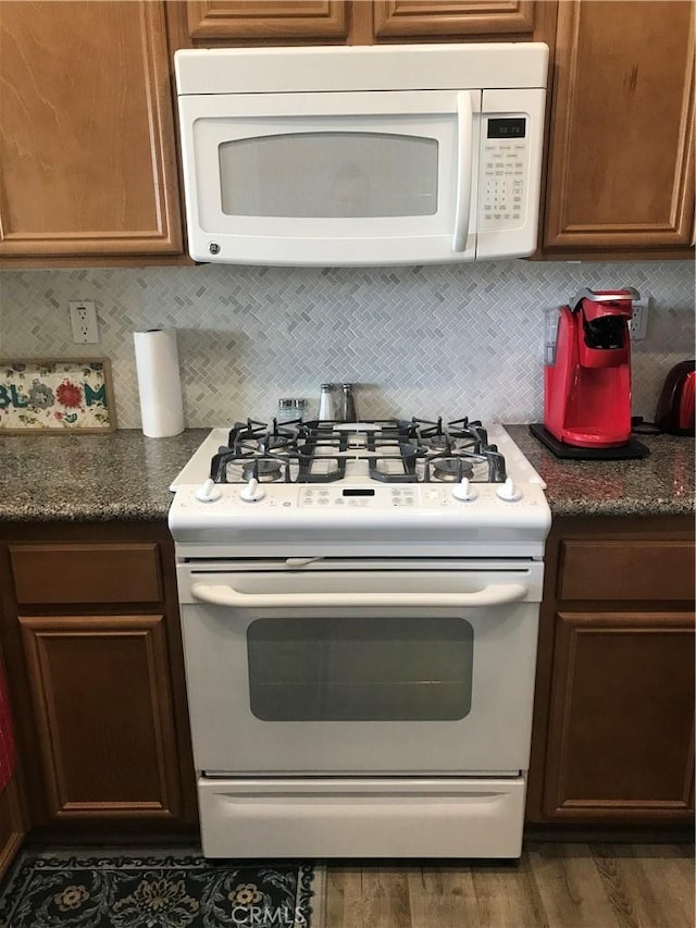 kitchen with white appliances, decorative backsplash, and wood finished floors