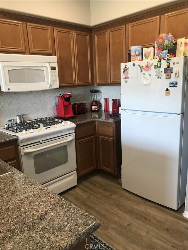 kitchen featuring tasteful backsplash, white appliances, brown cabinetry, and dark wood finished floors