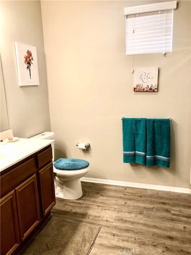 bathroom featuring baseboards, vanity, toilet, and wood finished floors