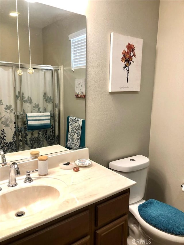 bathroom with a stall shower, vanity, and toilet