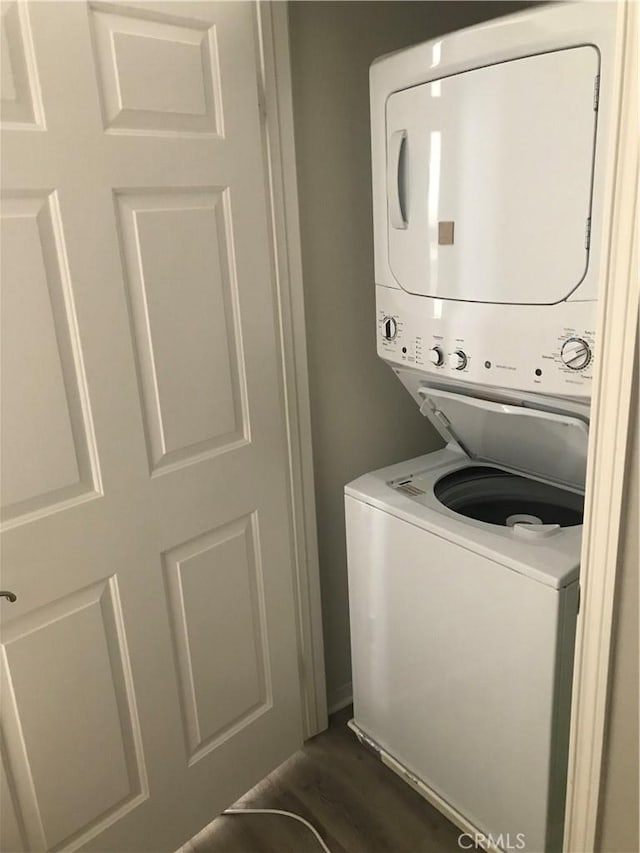 laundry room with stacked washer / drying machine, laundry area, and dark wood-style flooring