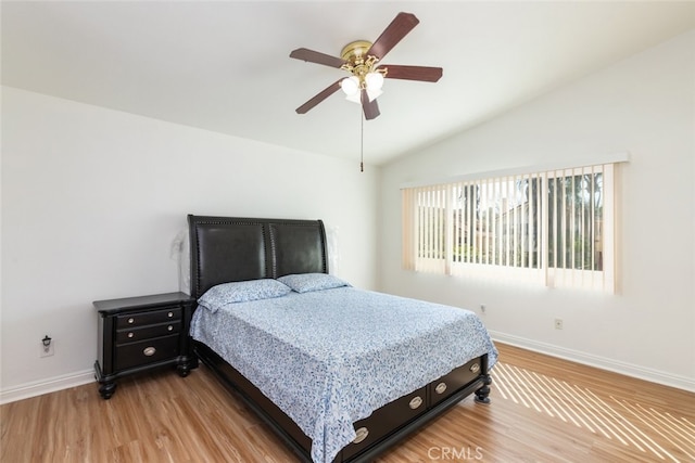 bedroom featuring light wood-type flooring, lofted ceiling, baseboards, and a ceiling fan