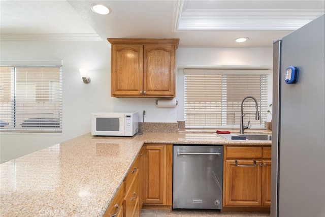 kitchen with white microwave, a sink, ornamental molding, stainless steel dishwasher, and light stone countertops