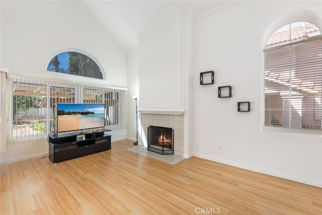 living room featuring high vaulted ceiling, a fireplace, wood finished floors, and baseboards