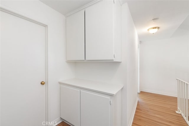 hallway featuring light wood-style flooring and baseboards