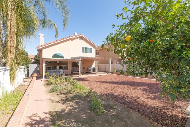 back of property with a patio, a chimney, a fenced backyard, and stucco siding