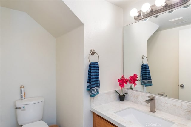 bathroom with toilet, visible vents, lofted ceiling, and vanity