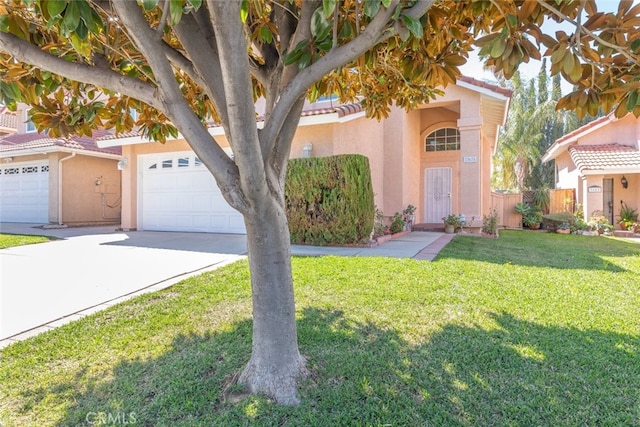 view of front of property featuring a garage, a tiled roof, concrete driveway, stucco siding, and a front yard