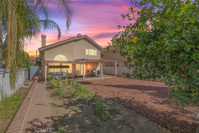 back of house with a patio, a chimney, a fenced backyard, and stucco siding