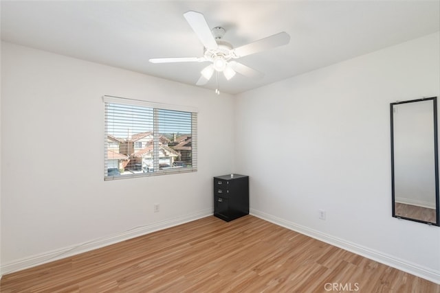 spare room with baseboards, a ceiling fan, and light wood-style floors