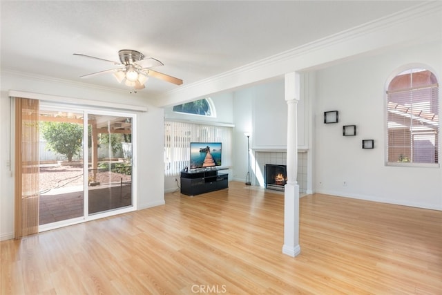 unfurnished living room featuring baseboards, a tiled fireplace, a ceiling fan, ornamental molding, and light wood-style floors