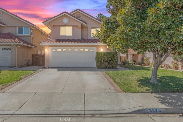 traditional-style home with an attached garage, a yard, driveway, a tiled roof, and stucco siding