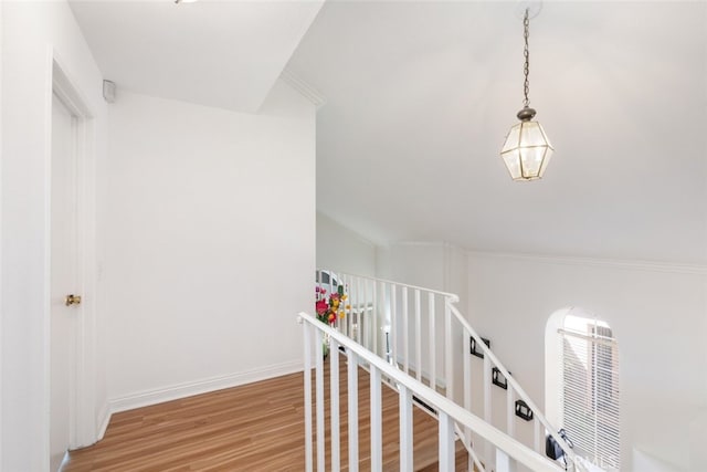 hall with baseboards, wood finished floors, and an upstairs landing