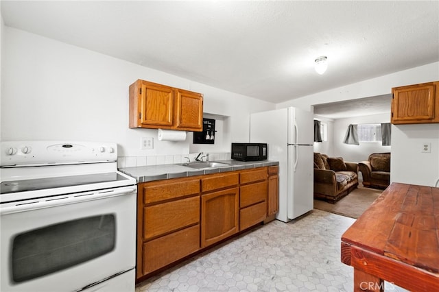 kitchen with brown cabinetry, white appliances, a sink, and tile countertops