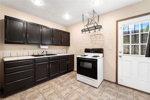 kitchen with a sink, light tile patterned floors, electric range oven, and recessed lighting