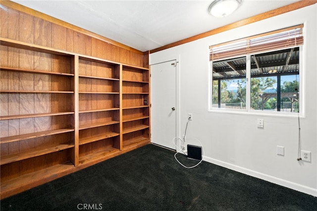 empty room featuring dark colored carpet and baseboards