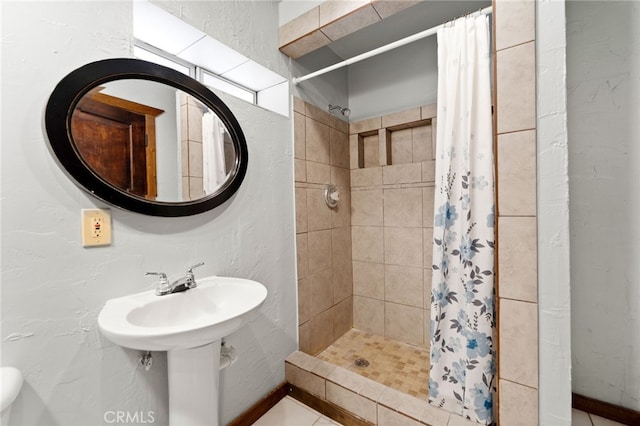 bathroom with a textured wall and a stall shower