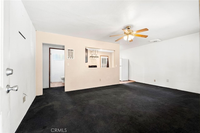 spare room featuring ceiling fan, visible vents, and dark colored carpet