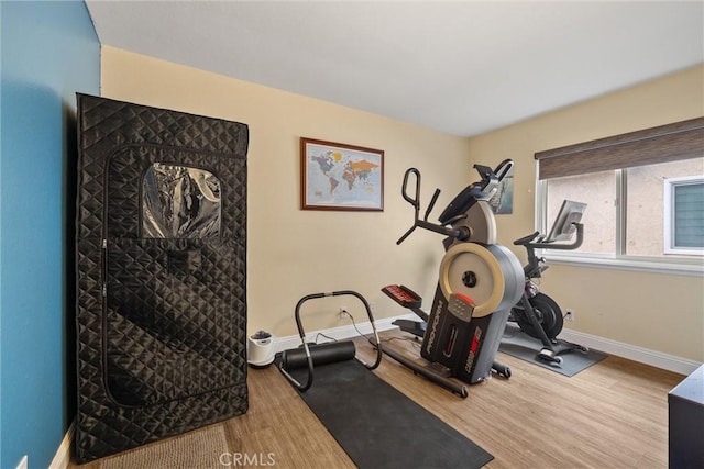 workout room featuring baseboards and wood finished floors