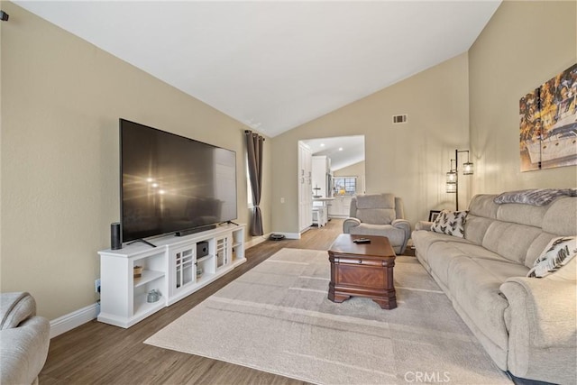 living area with visible vents, vaulted ceiling, baseboards, and wood finished floors